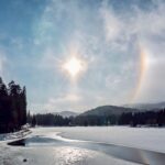 Stunning view of a sun halo over a winter landscape with a frozen lake.